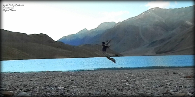 a man caught in mid air jumping next to a lake